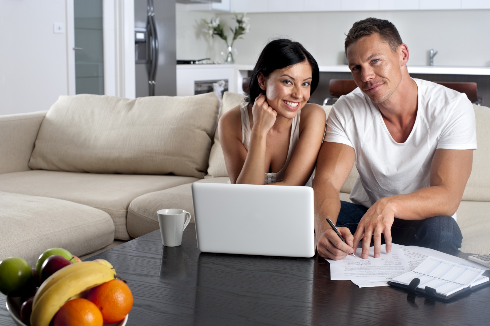 Couple doing paperwork with a laptop computer on the sofa
