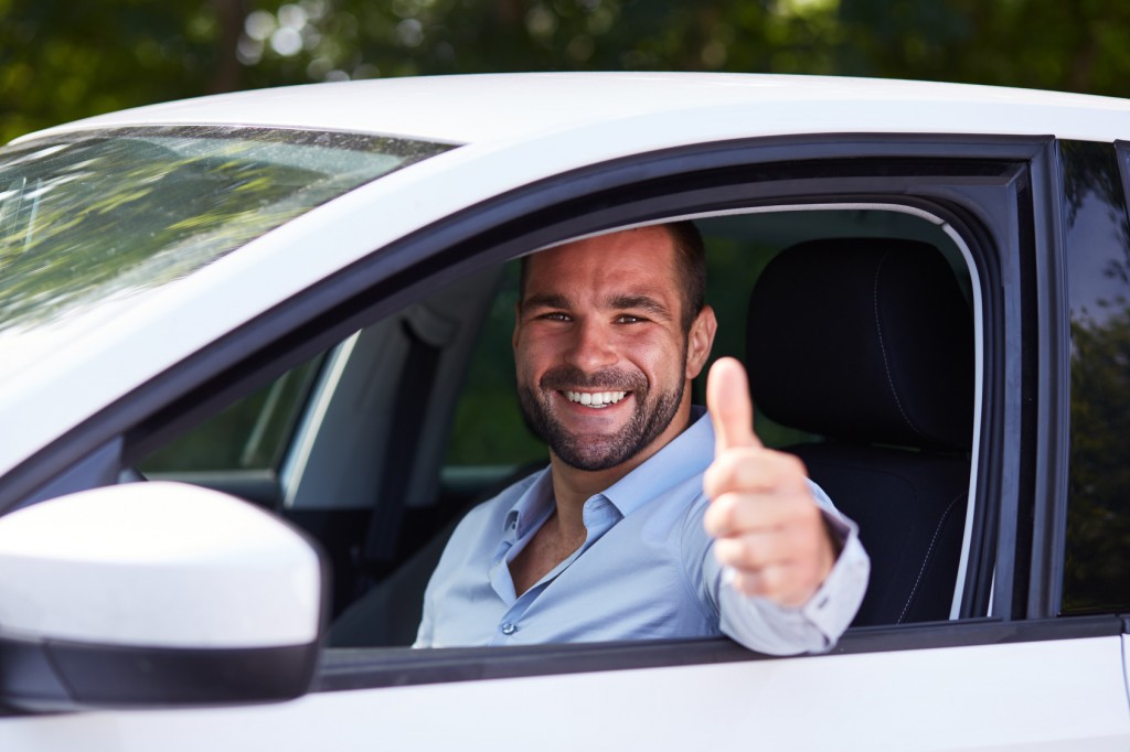 Man driving his car and makes gesture with thumb up