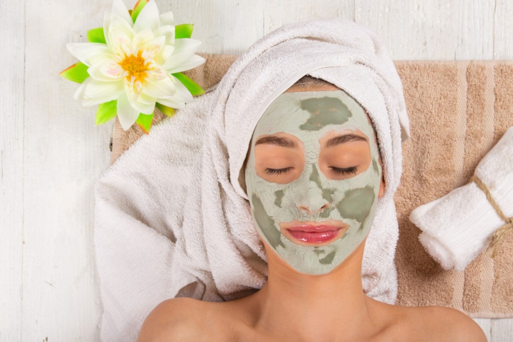 Young healthy woman in spa making treatments and face mask.